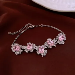 Exquisite silver-tone bracelet with pink floral zircon stones on dark red satin background