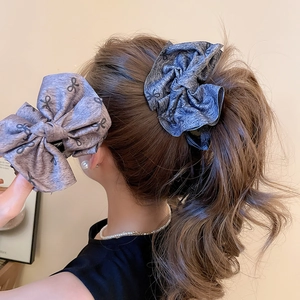 Detailed view of large fabric bow hair clips in grey and purple on a model