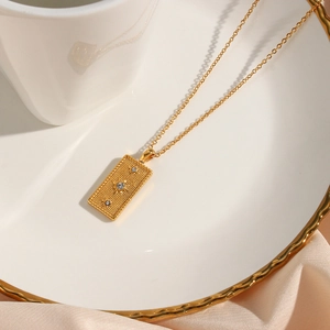 Detail of gold sun tarot pendant necklace with cubic zirconia in a white porcelain dish