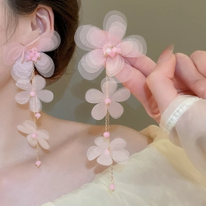 Detail view of pink chiffon flower tassel earrings worn to show the long elegant drop style
