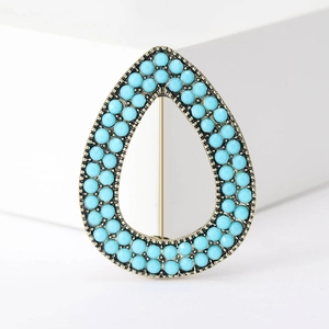 Detailed close-up of water drop brooch with antique bronze frame and turquoise blue beads