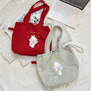 Detail of red and green drawstring canvas tote bags featuring cute sheep embroidery