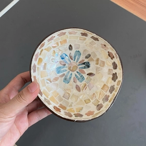 Detailed close-up of handmade coconut shell bowl with iridescent shell mosaic inlay