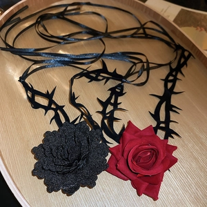 Detail eines Gothic-Halsbands mit Rosen und schwarzen Bändern auf Holztablett