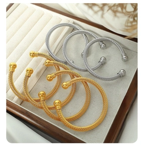 Detailed view of gold and silver twisted cable cuffs with ball ends on velvet display