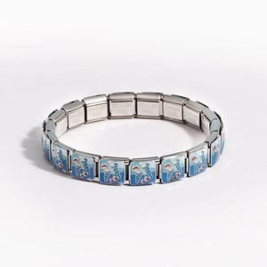 Macro detail of Italian modular bracelet links with blue enamel ocean waves on stainless steel