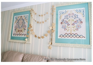 Golden star paper garland hanging in front of a modern living room wall decor