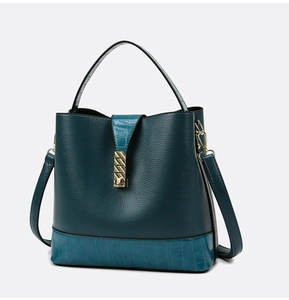 Macro view of dark cyan bucket bag featuring lychee pattern and crocodile embossed leather