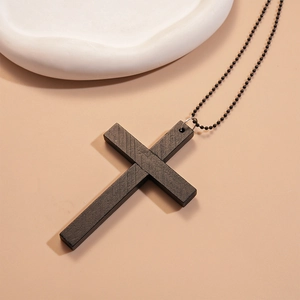 Détail d'un pendentif croix en bois foncé avec texture naturelle et chaîne à billes