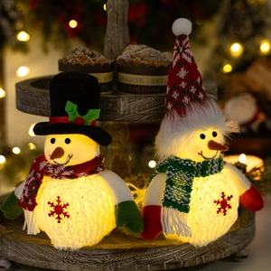 Close-up of glowing plush snowman dolls with LED lights and snowflake patterns on wood