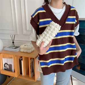 Brown striped V-neck knitted vest with navy and yellow accents in a cozy home setting