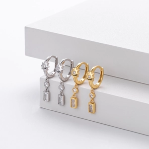 Detail of S925 silver and gold huggie hoop earrings with star charms and square zircons