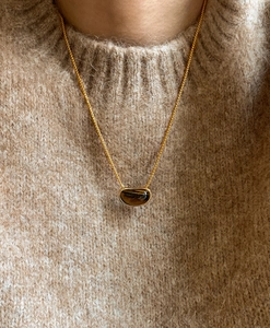 Close-up of 18k gold plated tiger eye pea pendant necklace on a beige sweater