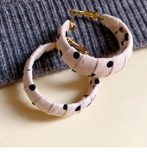 Close-up of retro geometric hoop earrings with pink polka dot fabric texture