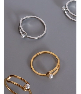 Macro shot of gold and silver geometric open rings with elegant white pearl accents