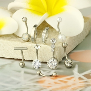 Detailed set of stainless steel belly rings with zircons and pearls on stone surface