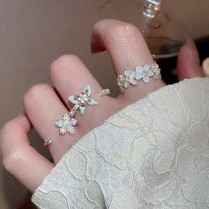 Vue détaillée de deux bagues fleurs ajustables avec zircon, perles et émail bleu