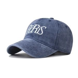Dettaglio del ricamo bianco PARIS su un cappellino in cotone lavato blu scuro