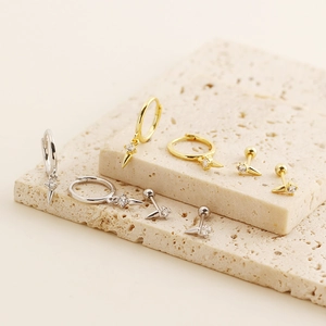 Detailed set of silver and gold spiked rivet earrings with crystal inlay on stone base