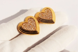 Détail macro de boucles d'oreilles cœur dorées avec pavé de zircons blancs brillants