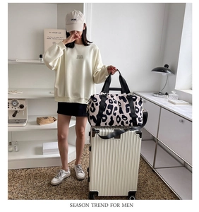Detail of leopard print travel bag with black handles on a white suitcase