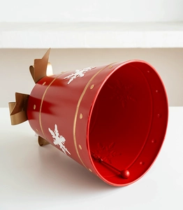 Close-up of a large red Christmas bell with gold bow, white snowflakes and metal clapper