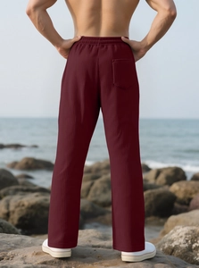 Detail of burgundy wide-leg trousers showing elastic waist and back pocket on model