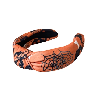 Handmade knotted Halloween headband featuring orange fabric with black spiderweb patterns