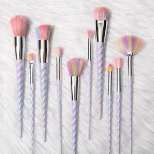 Unicorn makeup brush set with 10 rainbow bristle brushes on white fur background