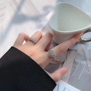 Close-up of heart-shaped sparkling ring and pavé band worn on a model's hand