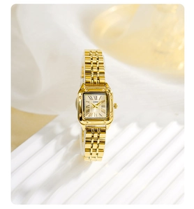 Detailed macro view of square gold watch face with Roman numerals and metal link strap