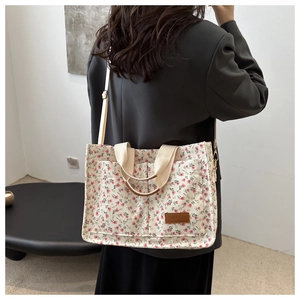 Detail of pink floral tote bag showing side pockets and crossbody strap worn by a model