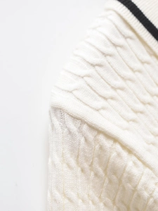 Close-up of cream cable knit texture and black striped collar detail on the sweater