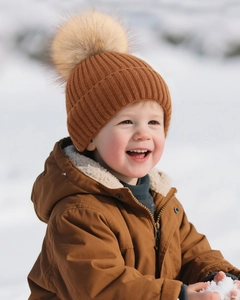 Winter knit baby beanie in caramel brown with large faux fur pompom and ribbed texture