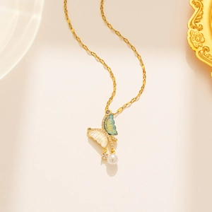 Detailed shot of golden butterfly pendant with blue gradient wings and white pearl drop