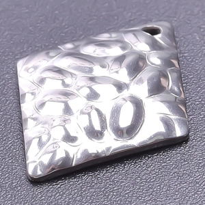 Macro view of a square hammered metal pendant with 18k gold plating and textured finish