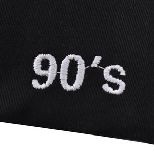 Close-up of white 90's letter embroidery on black twill fabric baseball cap