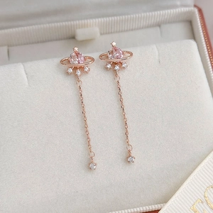 Macro shot of rose gold planet earrings with pink gems and stars in a jewelry box