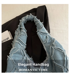Close-up of light blue denim shoulder bag with frayed tassels and quilted texture details