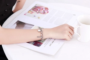 Detail of a double-layer stainless steel bracelet featuring padlock and key charms