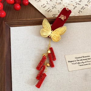 Detail of red velvet butterfly hair clip with golden character and long tassel accents
