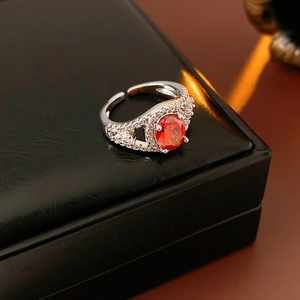 Macro shot of an adjustable silver ring with red oval gemstone and pavé zircon accents