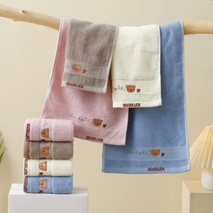 Close-up of soft cotton face towels with cute bear embroidery and decorative tassels