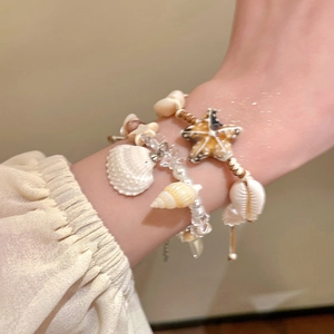 Detail of seashell and starfish charms on a stack of pearl beach vacation bracelets