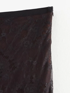 Detail shot of black floral lace stitching and side hidden zipper on elegant trousers