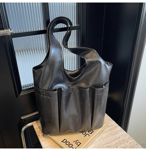 Detail of black soft leather tote bag with three vertical pockets and rivet accents
