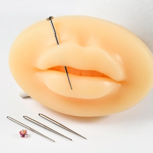 Close-up of a pink heart labret stud being inserted into a lip model with a guide needle