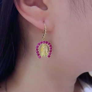 Close-up of gold Virgin Mary earrings with micro-set red gemstones and zircon inlay