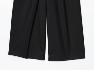 Detail of high-quality black woven fabric showing the drape and texture of wide-leg pants