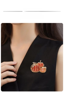 Close-up of sparkling pumpkin brooch with orange stones and rhinestones on black garment